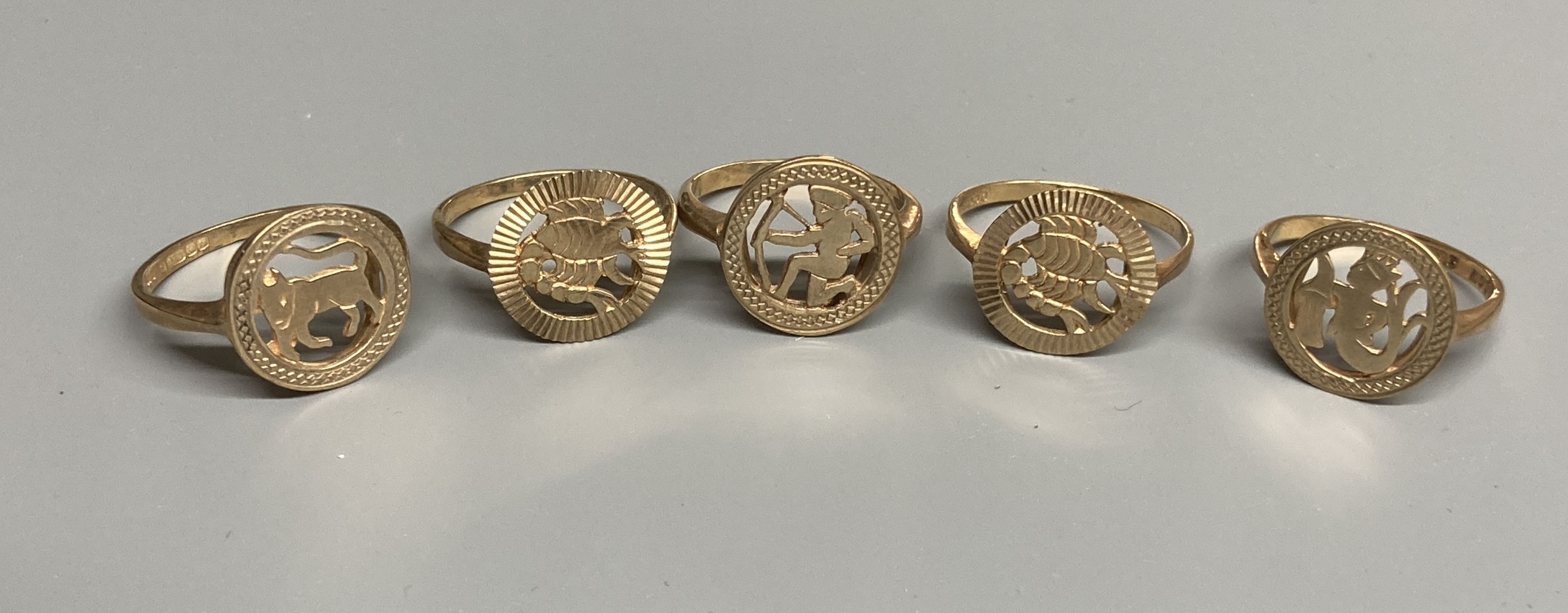 Four assorted modern 9ct gold 'Signs of the Zodiac' rings and one similar 9ct ring